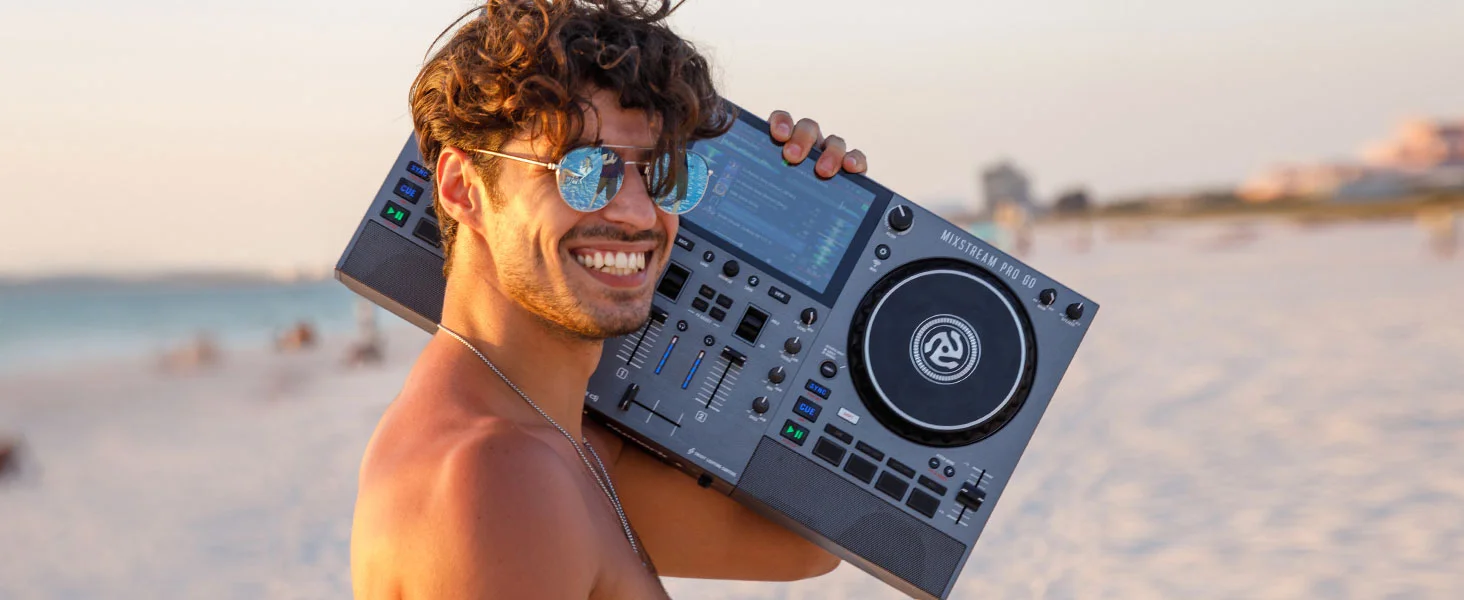 DJ en la playa donde se ve de medio hombro hasta toda la cabeza portando la controladora DJ Mixstream Pro GO