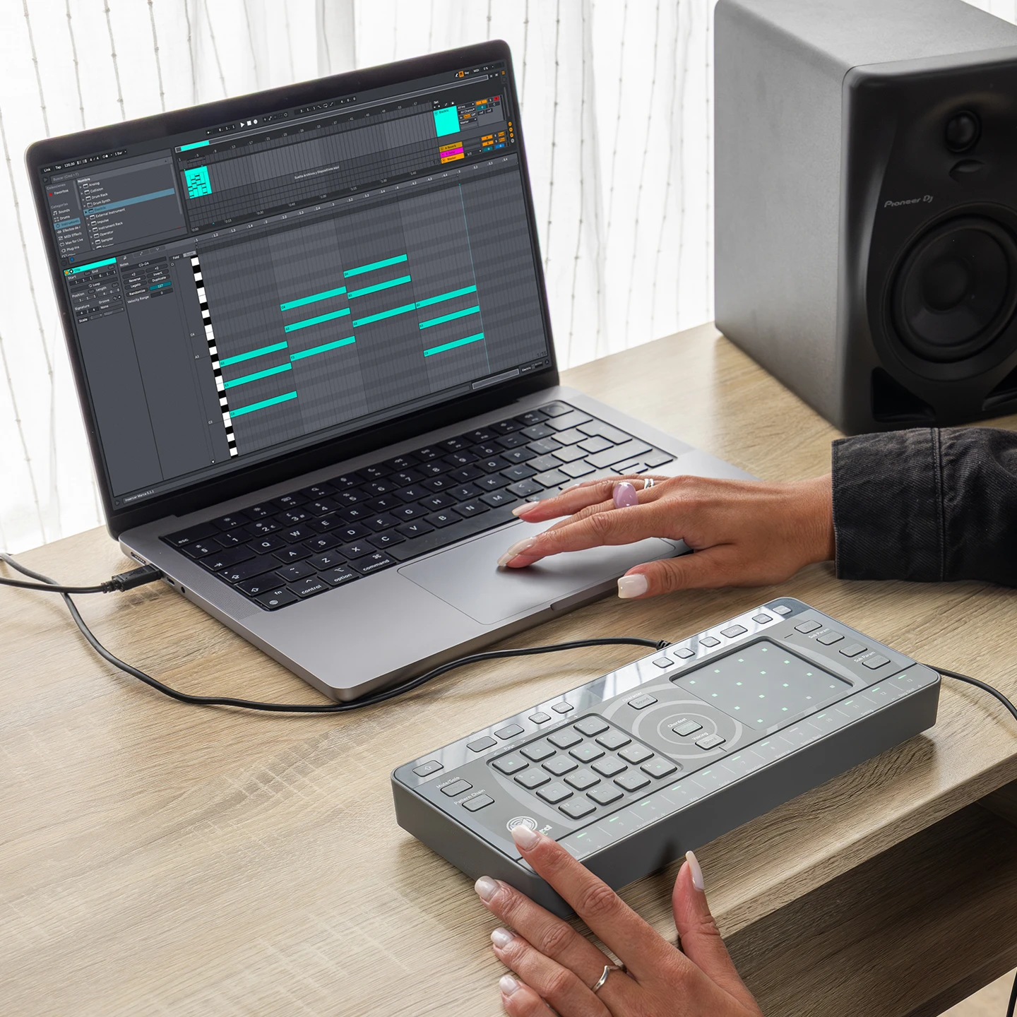 Persona utilizando un controlador MIDI Chordcast conectado a un portátil con software de producción musical, sobre un escritorio con altavoz de monitoreo Pioneer.