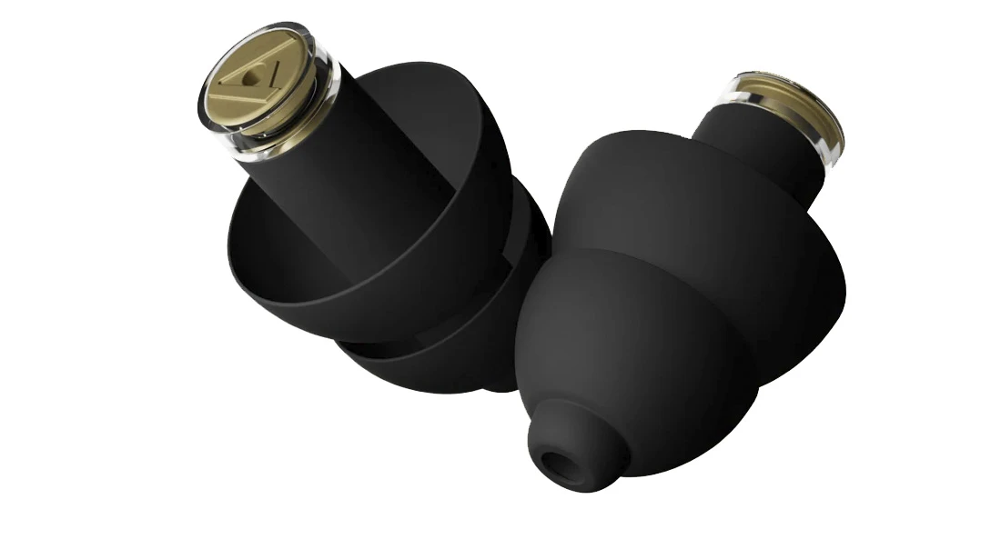 Primer plano macro de dos tapones auditivos Alpine MusicSafe Pro en silicona negra, mostrando los filtros acústicos dorables insertados y su diseño de láminas flexibles. 